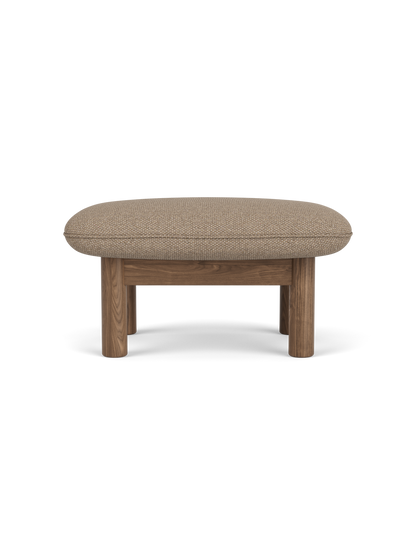 Side profile of the Brasilia Ottoman with a walnut frame and cushioned seat upholstered in textured Logan Flint fabric.