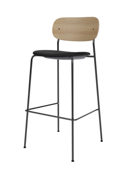 Co Bar Chair with a natural oak backrest and black upholstered seat on a slender black steel frame with footrest.