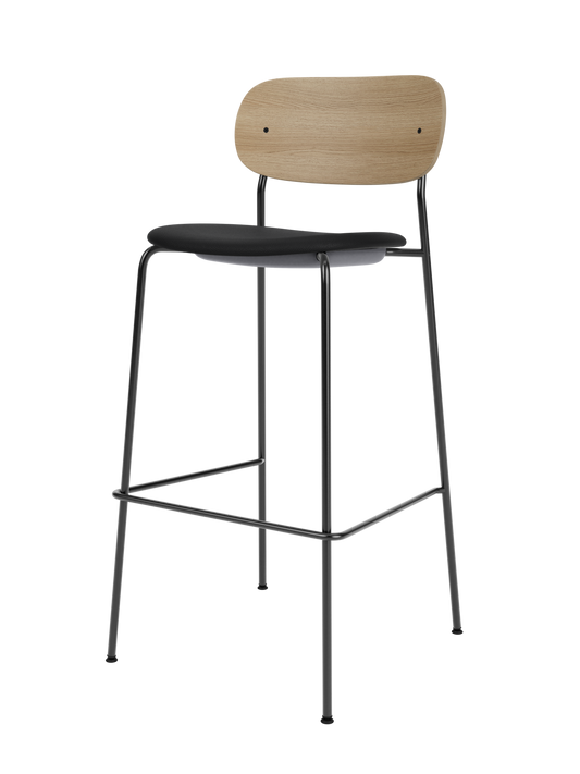 Co Bar Chair with a natural oak backrest and black upholstered seat on a slender black steel frame with footrest.