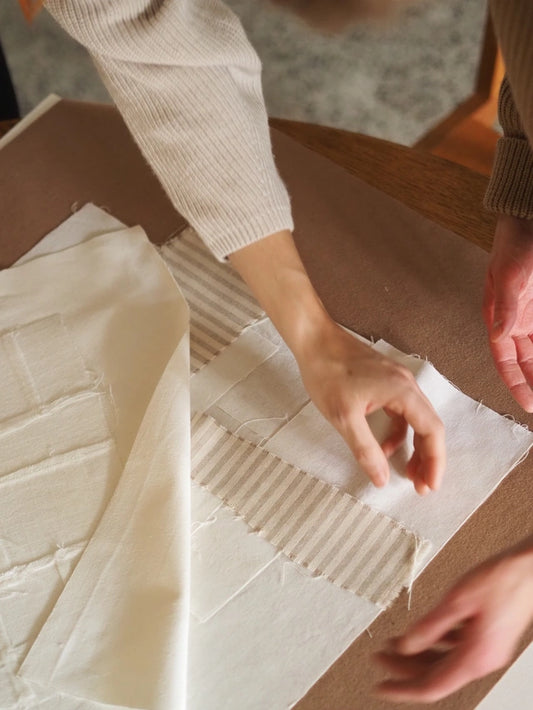 Hands arranging neutral and striped fabrics at the 'Ways of Seeing' Creative Workshop with Atelier Cph.