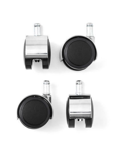 Top-down view of four caster wheels arranged in a grid. Each wheel is black plastic with a polished chrome housing and pin.