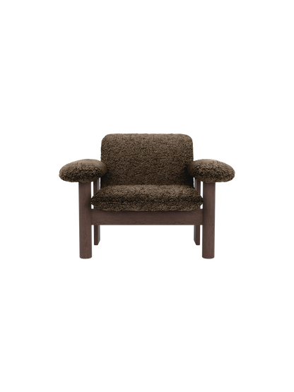 Front view of the Brasilia Lounge Chair, Low Back, in brown sheepskin with a dark stained oak frame on a black background.