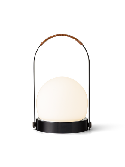 Carrie Portable Lamp featuring a glowing opal glass shade and black arched handle with a brown leather cord detail.