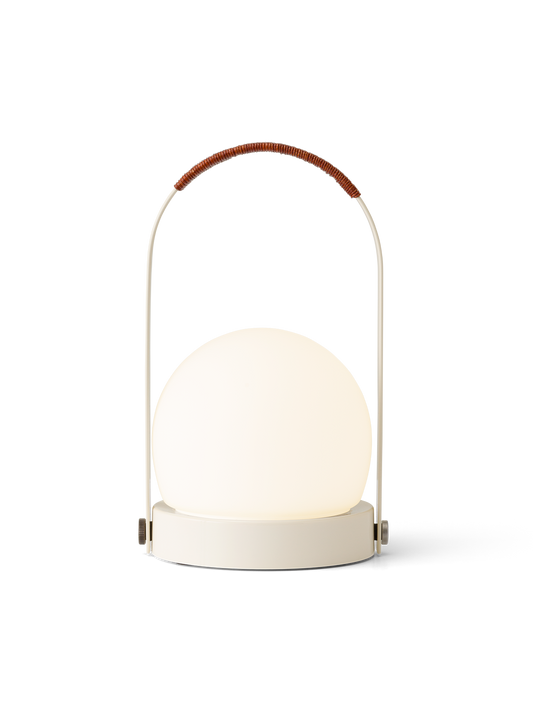 Illuminated Carrie Portable Lamp in ivory with a leather-wrapped handle and spherical opal glass shade.