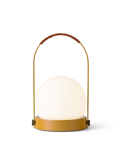 Golden brown Carrie Portable Lamp featuring an illuminated opal glass shade and a curved handle with leather cord detail.