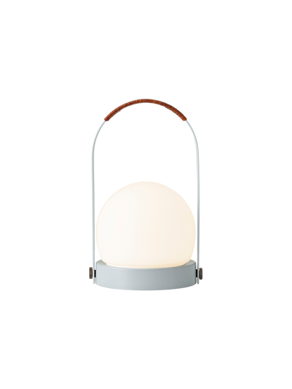 Portable Carrie Table Lamp in Linen Blue with an illuminated opal glass shade and a brown leather-wrapped handle.