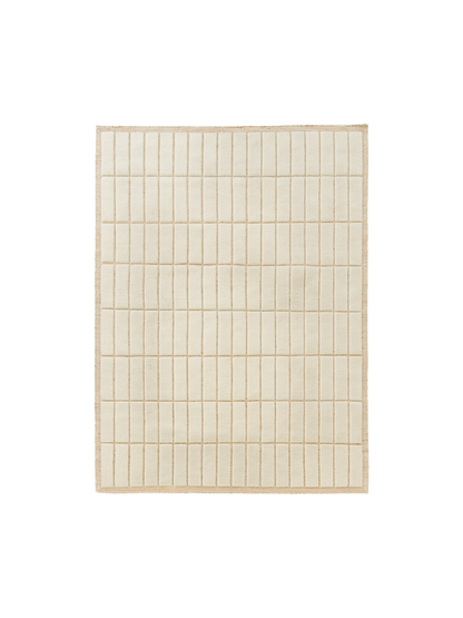 Top-down view of a square, light beige rug featuring a raised grid pattern of soft, rectangular tiles and a woven border.