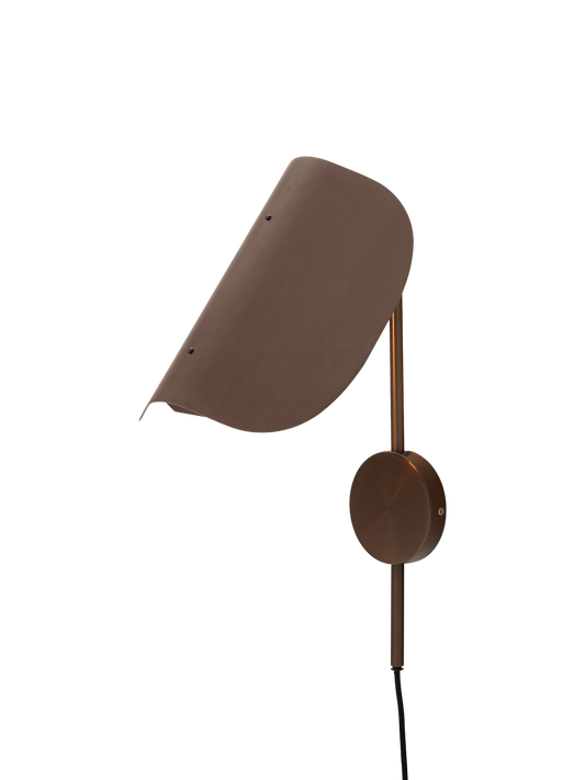 Angled view of the bronzed aluminium Wing Wall Lamp with its light on, highlighting the distinctive wing-shaped shade.