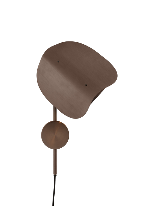 A close-up of the Wing Wall Lamp in bronzed aluminium, lit against a black background to show its sculptural, folded shade.