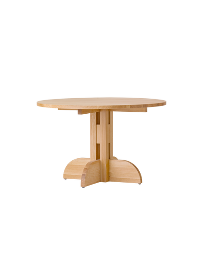 Puffin Dining Table in natural solid oak with a round top and architectural base, isolated on a white background.