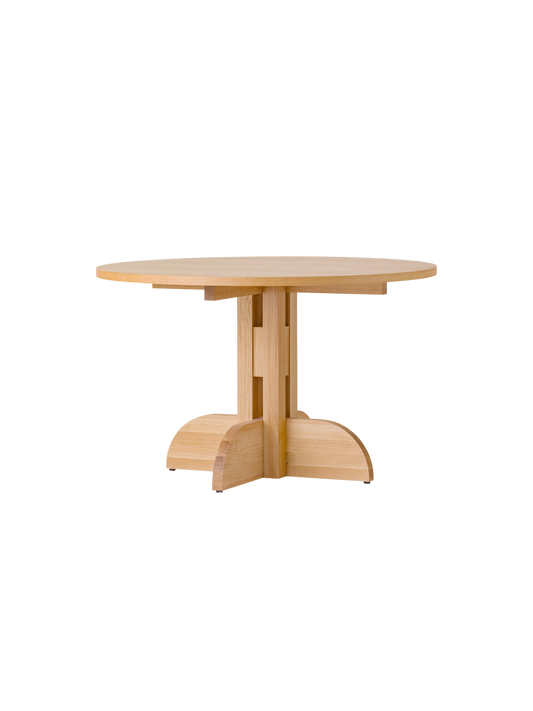 Puffin Dining Table, Round, in natural oak with a sculptural solid wood base, shown at an angle against a white background.