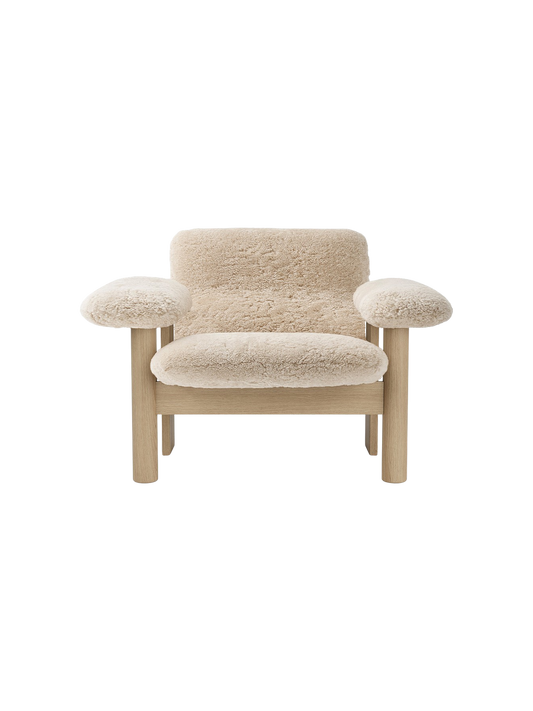 Front-on shot of the Brasilia Lounge Chair, Low Back. It has a light oak frame and is upholstered in fluffy, beige sheepskin.