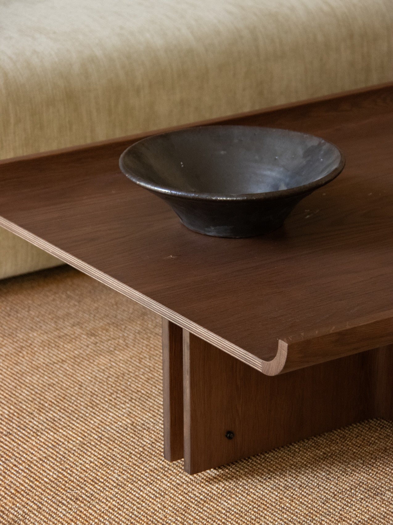Conrad Lounge Table in dark stained oak veneer with a decorative bowl on top, shown in a styled interior setting.
