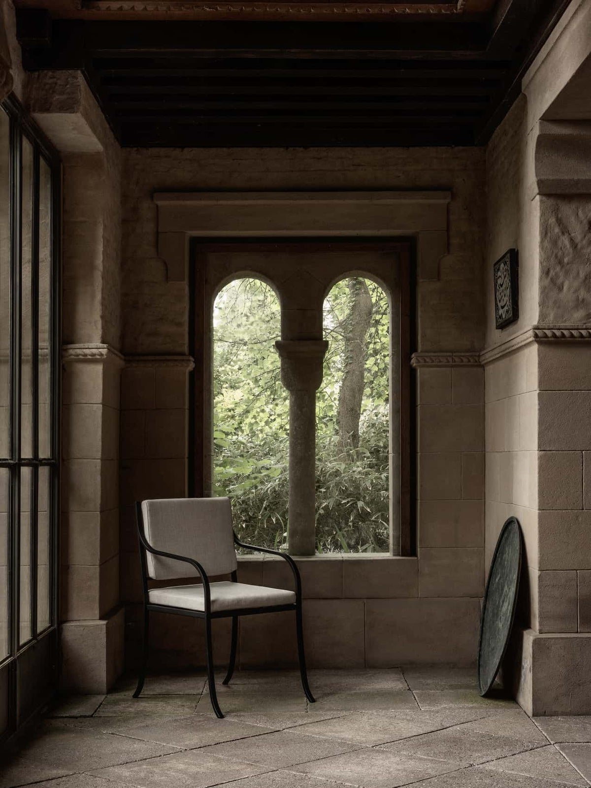 Bloss Garden Dining Chair in black steel with light cushions, on a stone porch.