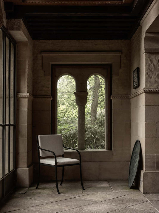 Bloss Garden Dining Chair in black steel with light cushions, on a stone porch.