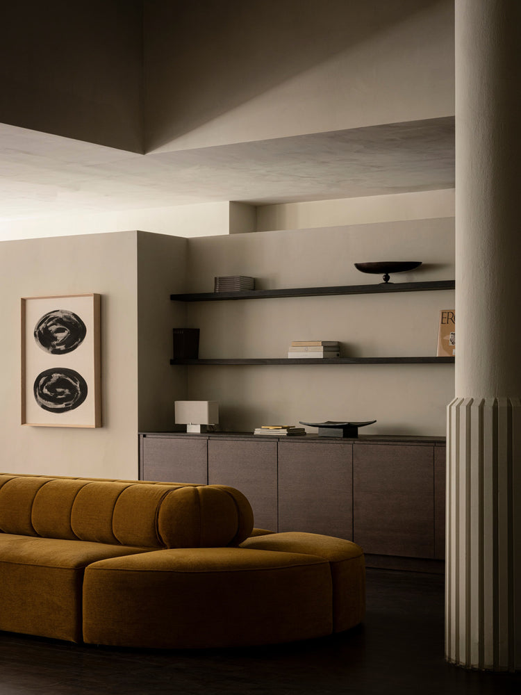 Minimal living room with mustard velvet curved sofa, dark wood cabinet and floating shelves with neutral decor