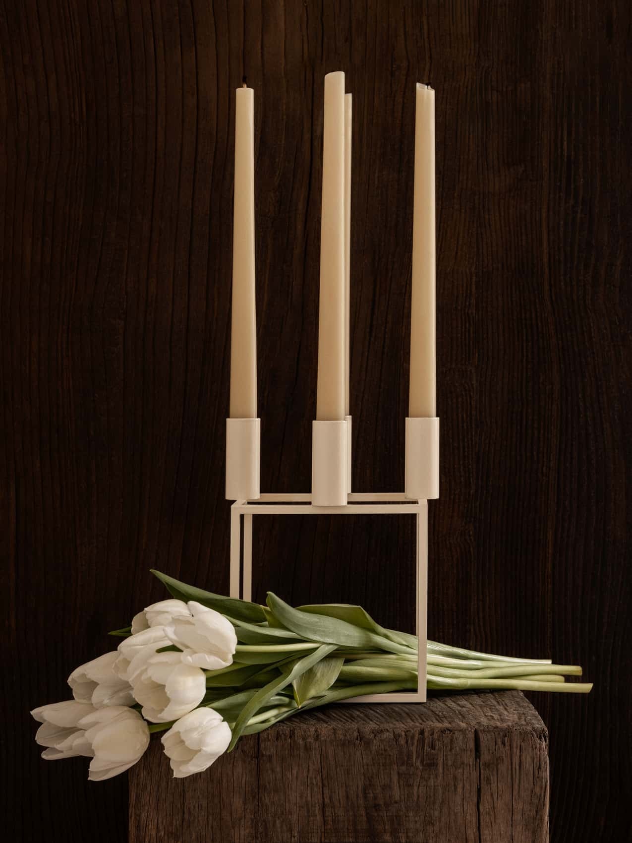 Kubus 4 candle holder styled on a shelf with a lit candle