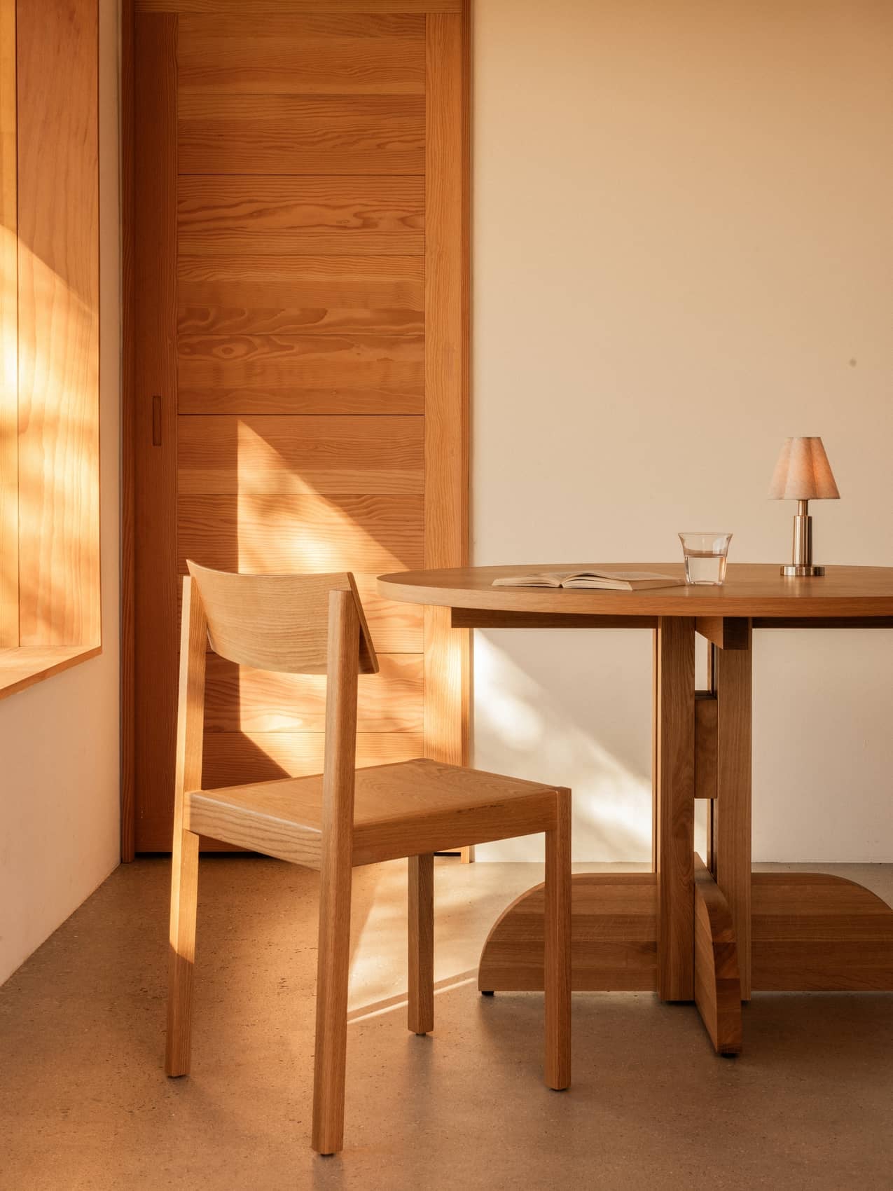 Solid oak Puffin Dining Table and Mauro Dining Chair in a sunlit interior with an Admiral Portable Table Lamp.