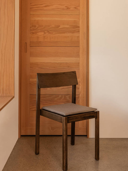Dark wood Mauro Dining Chair with a striped Seat Cushion, positioned against a light-coloured wooden door.