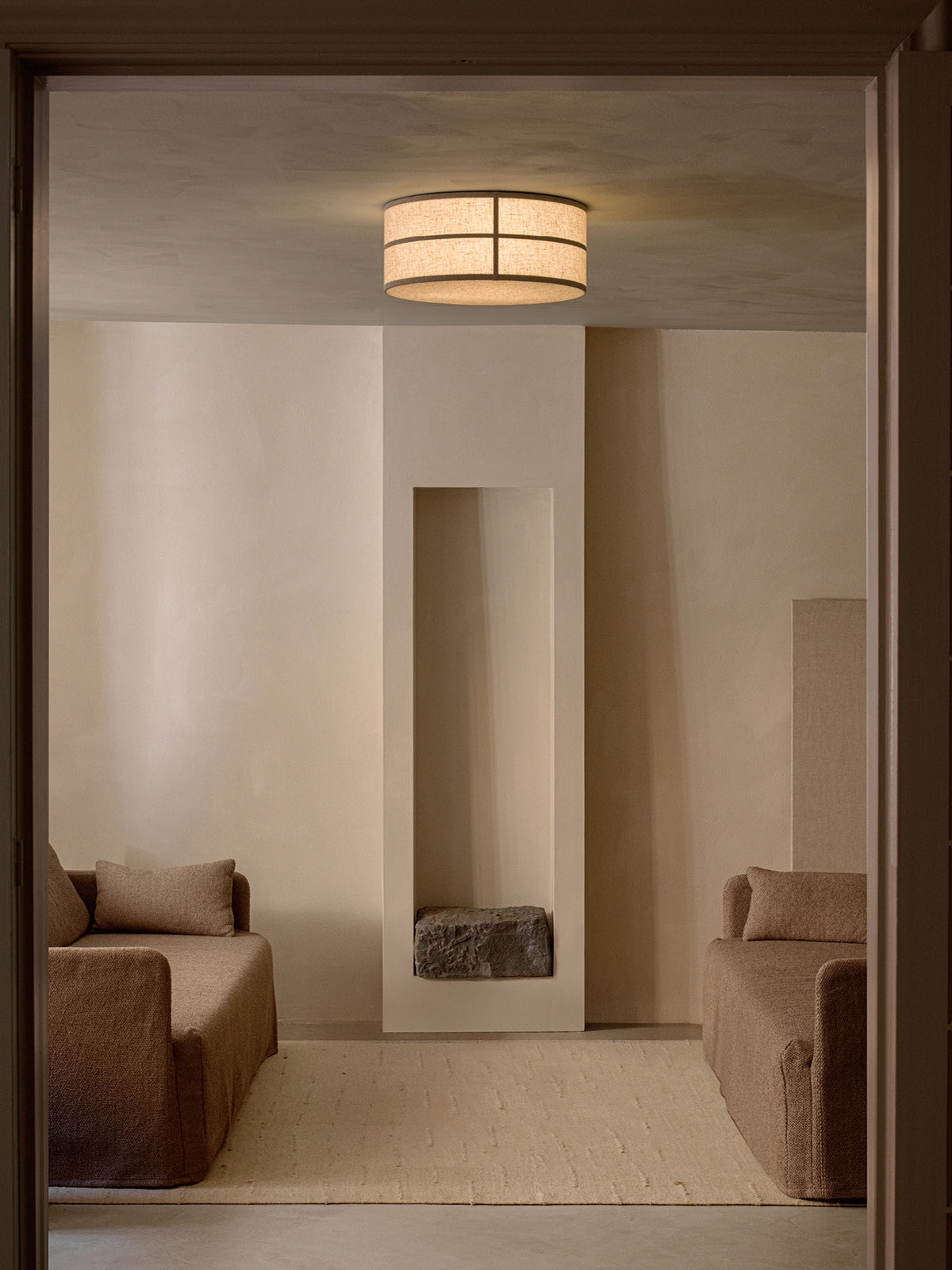 Hashira Ceiling Lamp in raw linen, mounted flush against a ceiling in a warmly lit, neutral-toned living room.