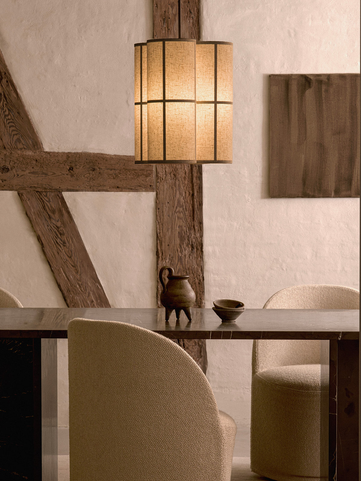 Hashira Pendant Lamp Cluster hanging above a dark dining table with upholstered chairs in a rustic interior.