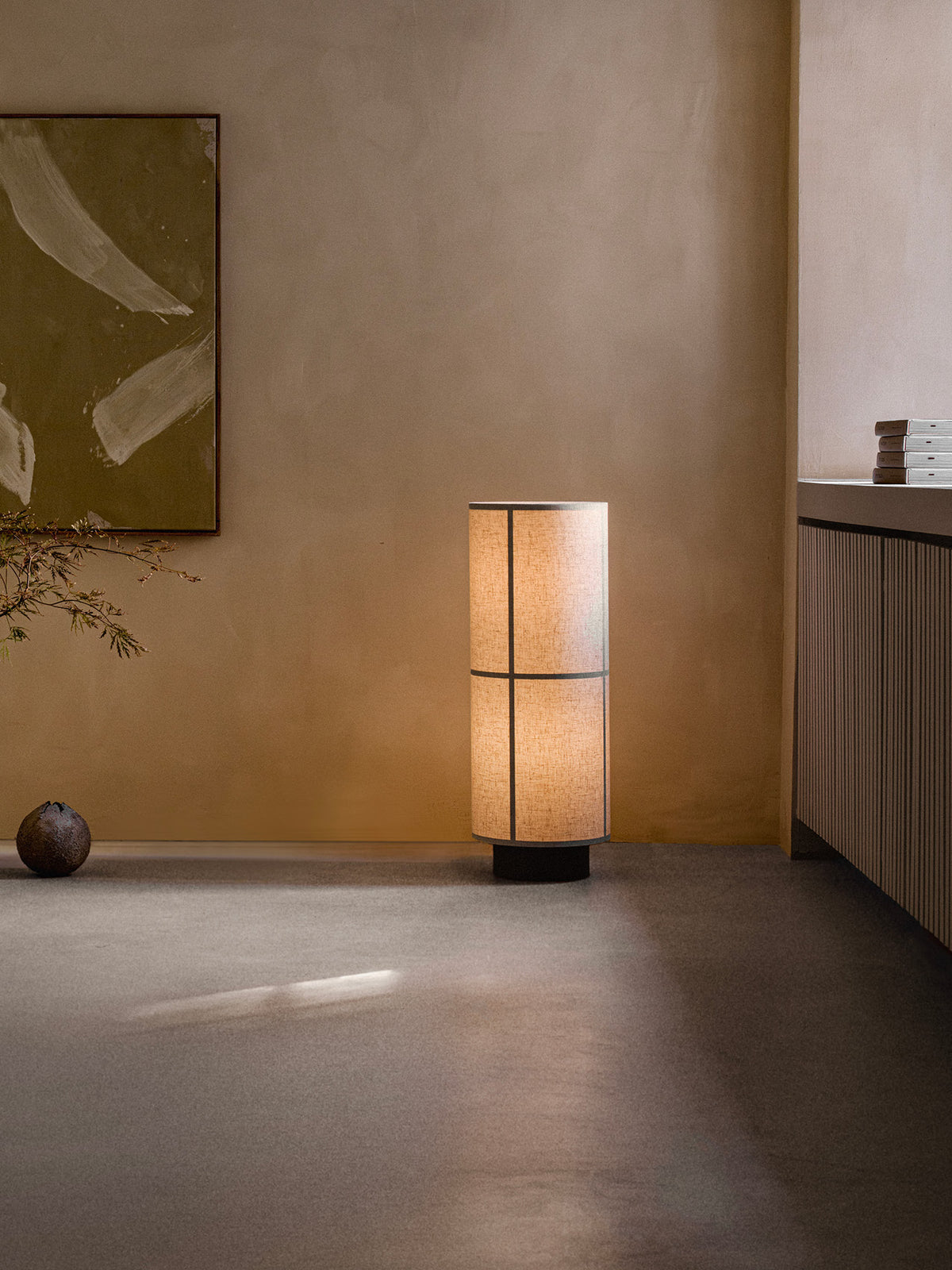 Hashira Floor Lamp in Raw, featuring a cylindrical translucent fabric shade, standing in a minimalist interior.