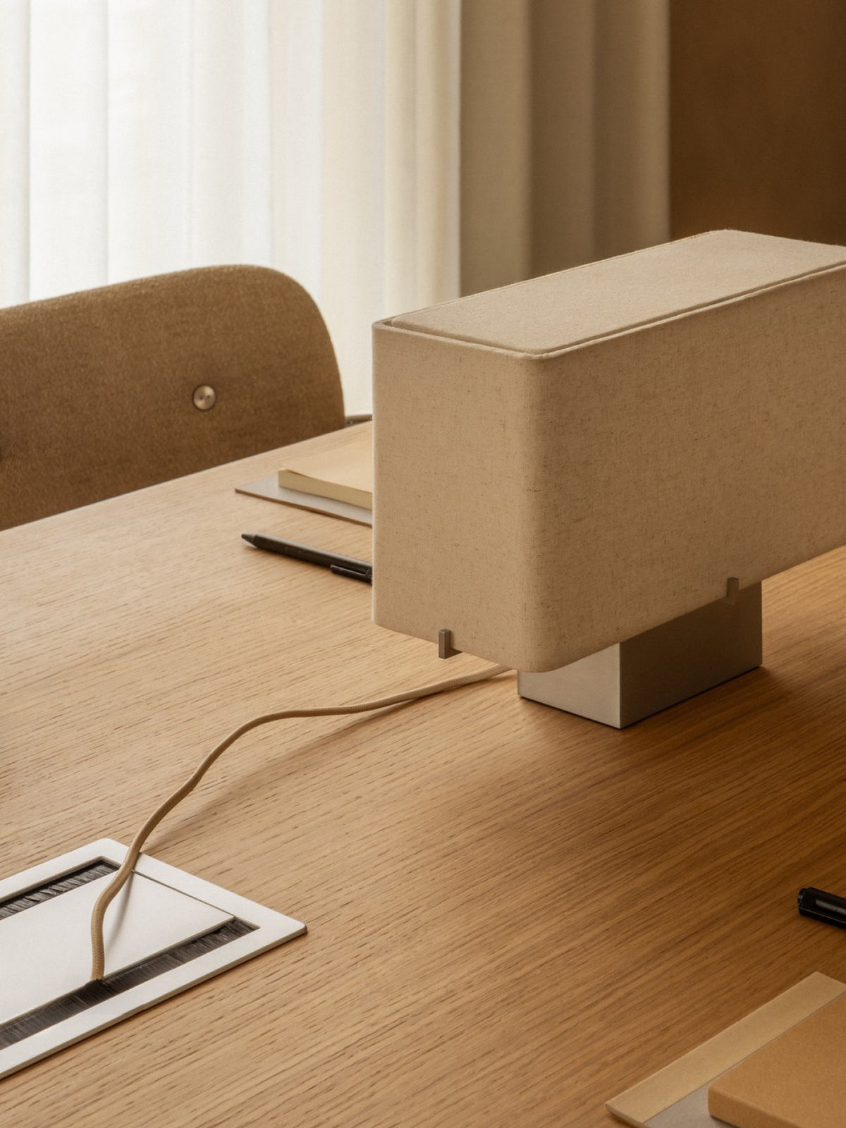 Cable Management in brushed aluminium integrated into a wooden office desk, featuring a power cord and a matching lamp.