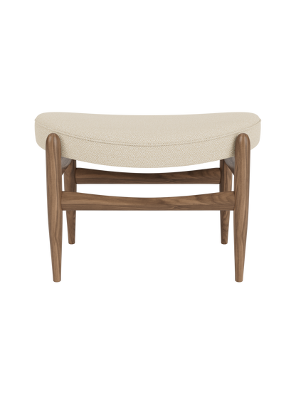 A front view of the Elizabeth Ottoman, with a walnut frame and a curved cushion upholstered in light Hallingdal fabric.