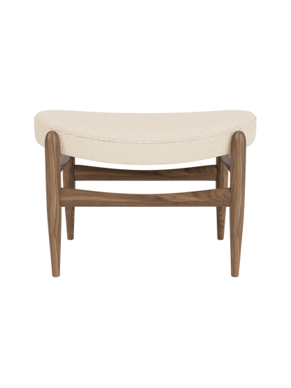 A front view of the Elizabeth Ottoman with a walnut wood frame and curved cushion upholstered in cream Logan Jasmine fabric.