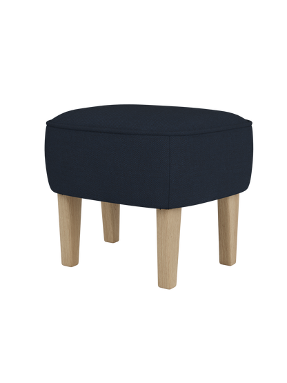 The Ingeborg Ottoman, with a dark blue textured textile seat and natural oak legs, viewed from a front-three-quarter angle.