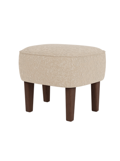 The Ingeborg Ottoman, shown from a three-quarter angle, with a textured light beige cushion and four tapered dark oak legs.