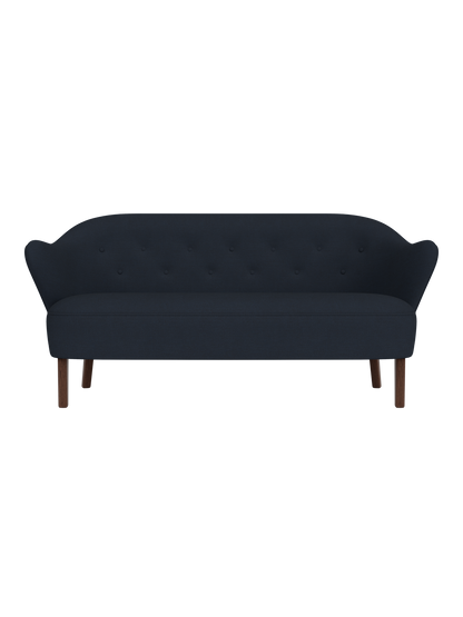 Front view of the Ingeborg Sofa in a dark navy blue textile, featuring a button-tufted back and smoked oak legs.