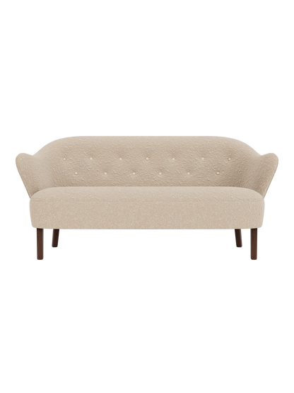 Front view of the Ingeborg Sofa in a textured light beige fabric with a buttoned back, flared arms and smoked oak legs.