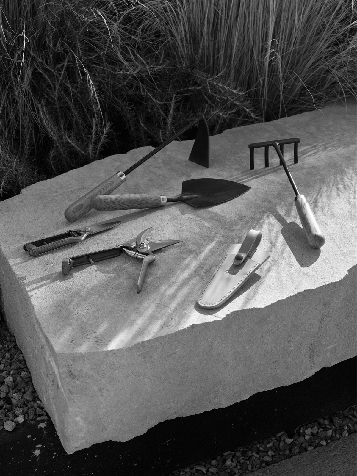 Pallares Plant Set featuring gardening tools with wooden handles and dark metal blades arranged on a stone surface.