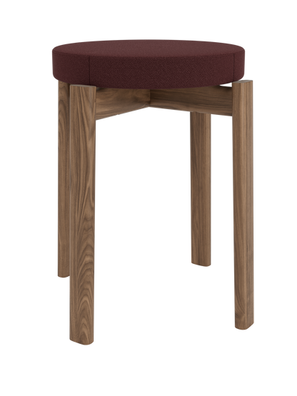 A front view of the Passage Stool, Upholstered. It has a dark walnut wood frame and a round, padded seat in deep red fabric.