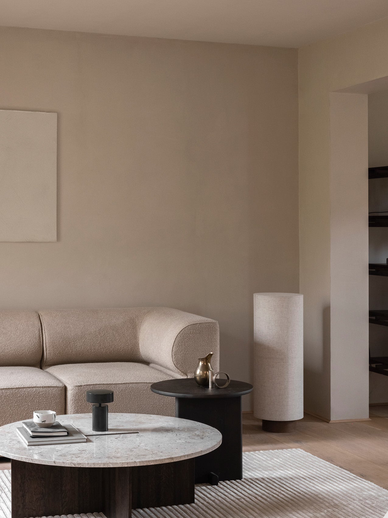 Minimal living room with curved beige boucle sofa, round marble coffee table, black side table and tall fabric floor lamp.
