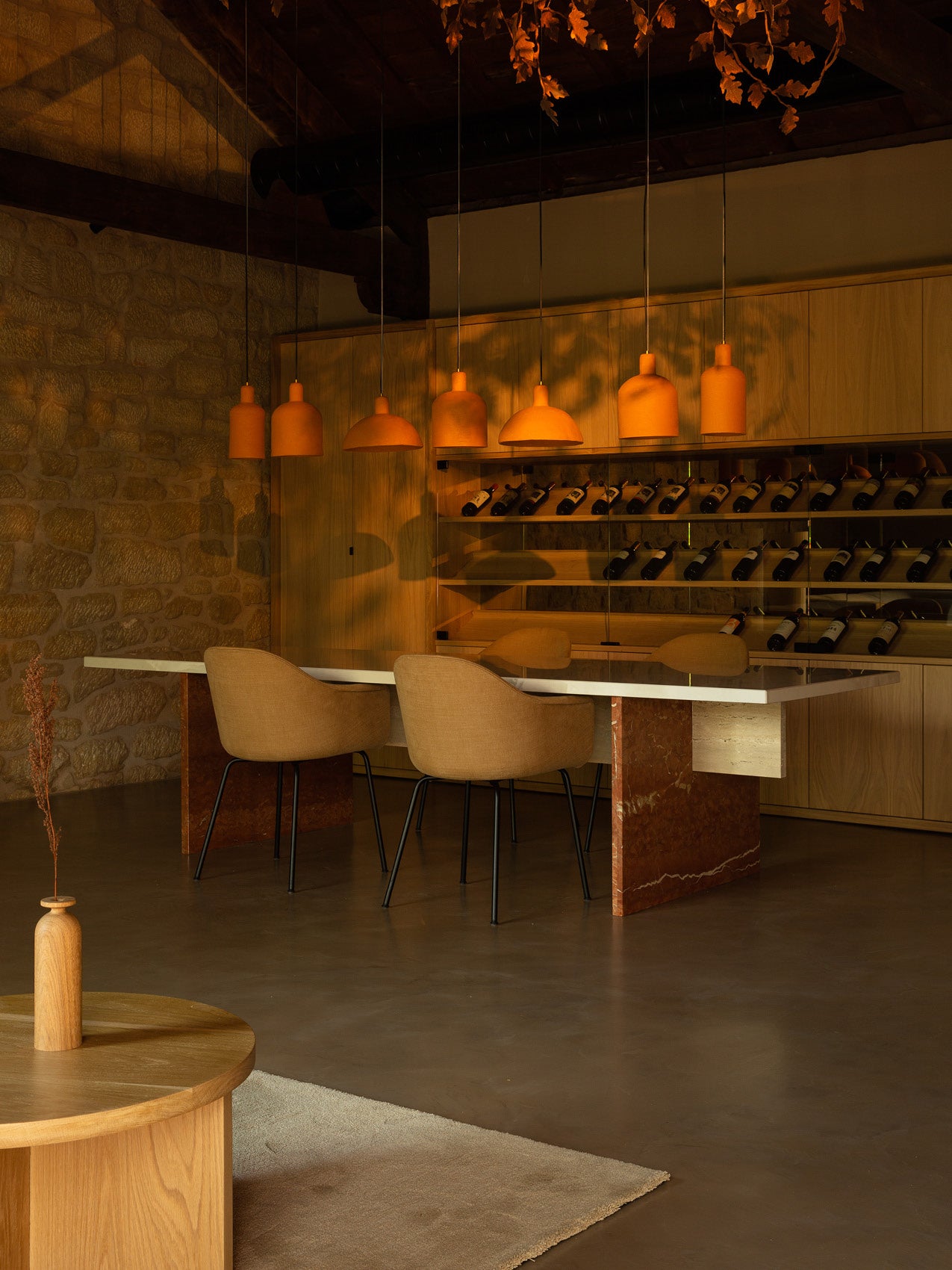 Warm dining area with six terracotta pendant lamps above a white-topped marble table and two beige upholstered chairs