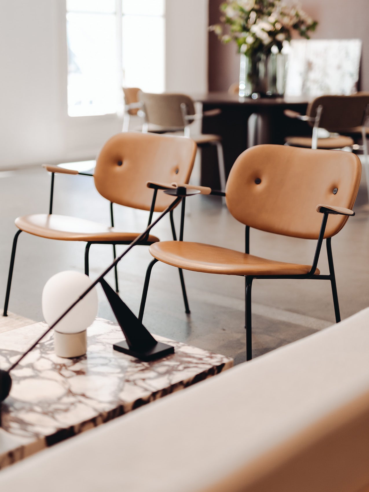 Pair of tan leather lounge chairs with black metal frames and rounded seats in a modern interior