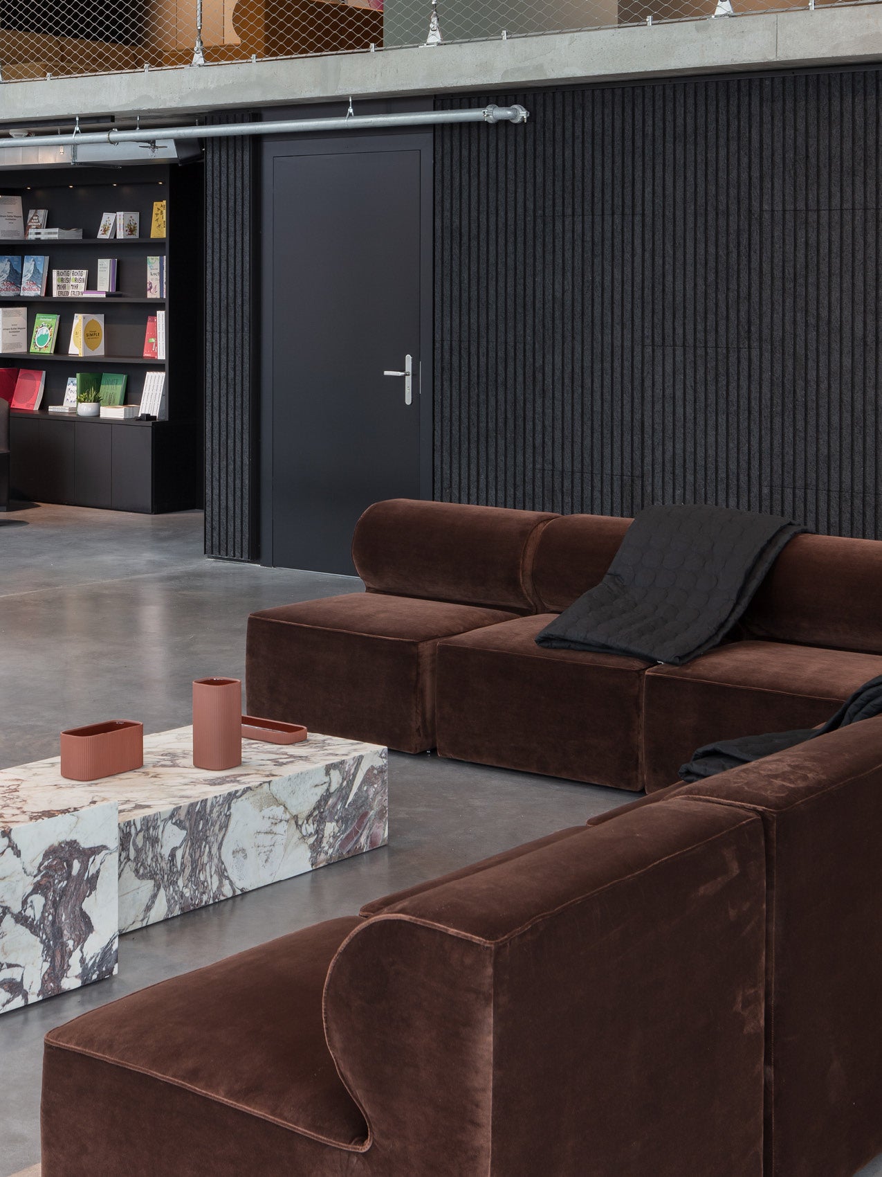 Brown velvet modular sofa with rounded armrests in modern lounge, marble low table with terracotta accessories and black