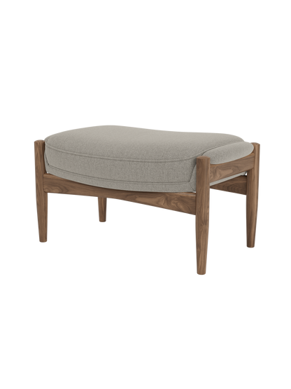 A studio shot of The Seal Ottoman, showing its oiled walnut frame and light grey Re-Wool 218 upholstered cushion.