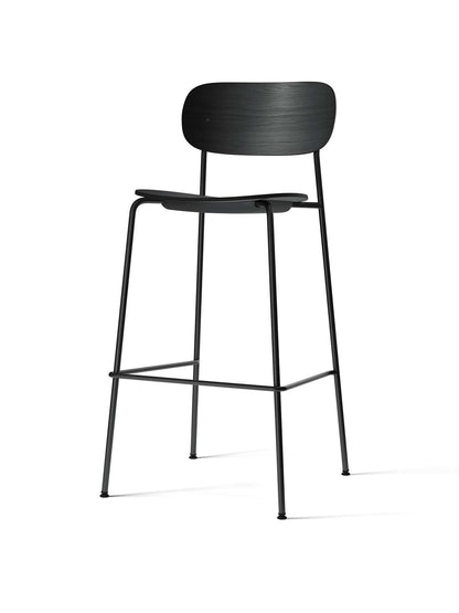 A Co Bar Chair with a black oak veneer seat and curved backrest, set on a slender black steel frame with footrests.