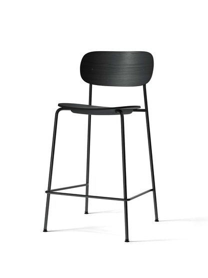 A black Co Counter Chair with a black oak veneer seat and backrest, set on a slim, tubular black steel frame with a footrest.