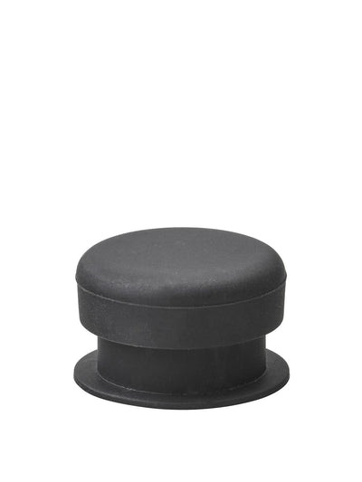 A close-up photograph of a small, cylindrical black component, likely a rubber stopper or foot, against a white background.