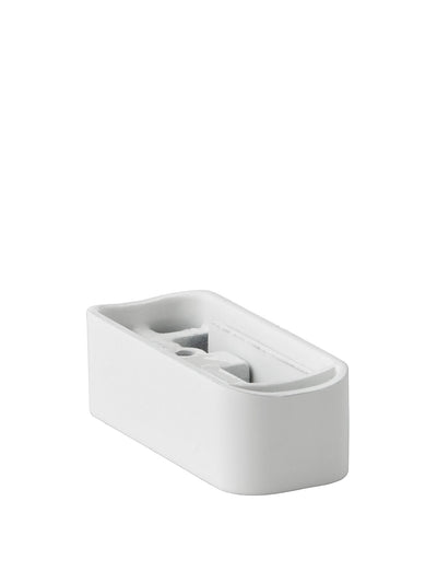 A rectangular white ceramic object, possibly a mounting base, with rounded corners and internal indentations.