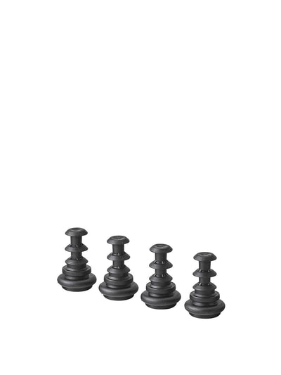 Four black rubber mushroom-shaped chair glides with stacked concentric rings, shown in a row on white background