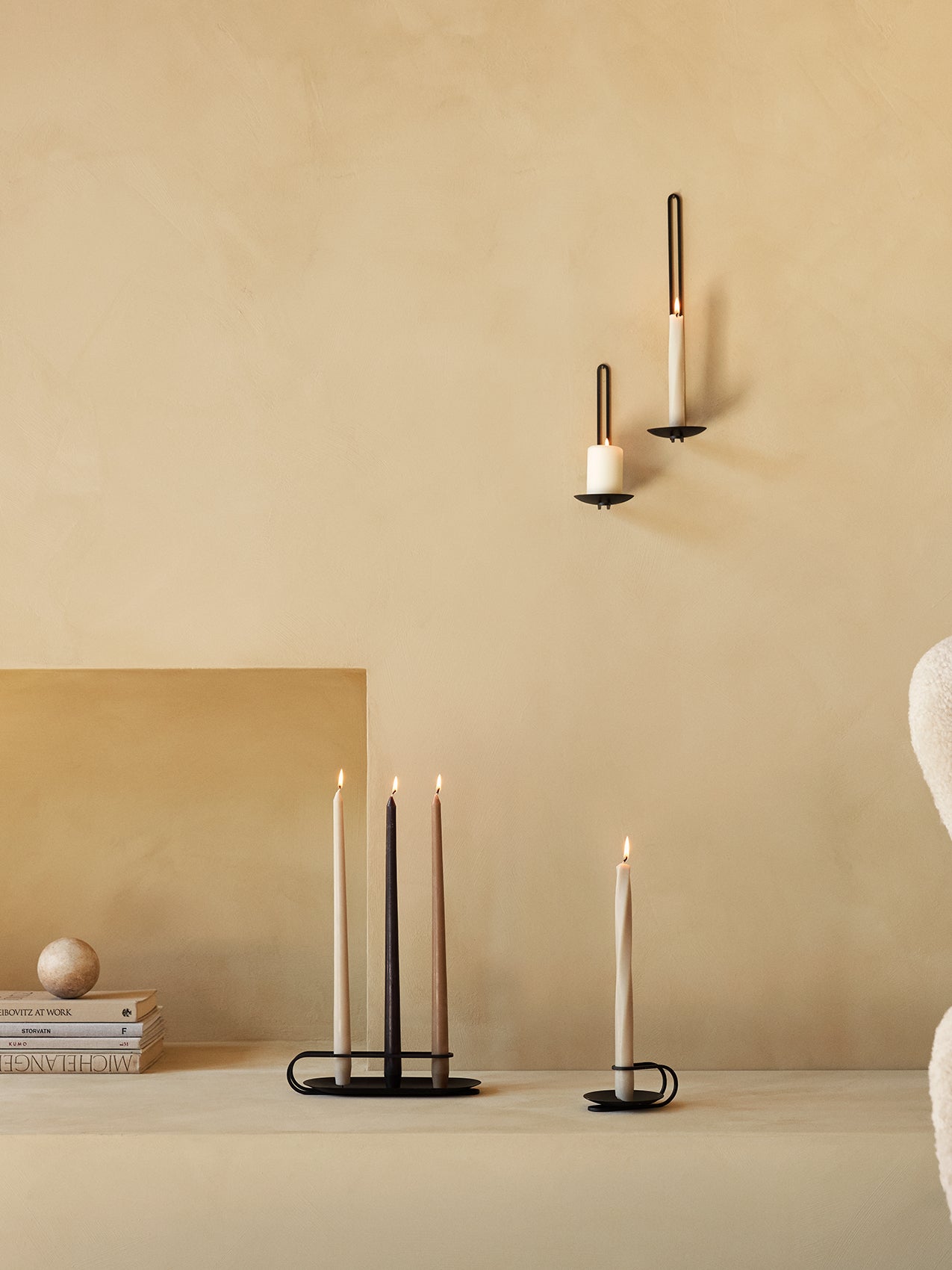 A collection of black metal Clip Candle Holders for wall and table use, holding various lit Spire and Twist Tapered Candles.